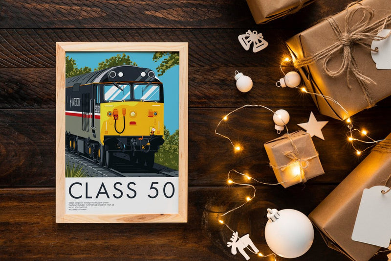Framed Class 50 print on a wooden table with fairy lights and wrapped presents