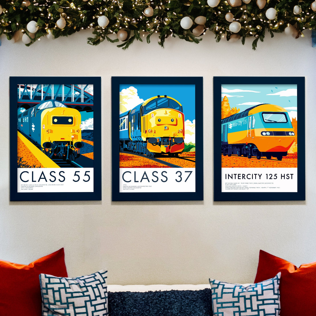 Three framed diesel locomotive prints, Class 55, Class 37 and InterCity 125, on a wall beneath a Christmas garland