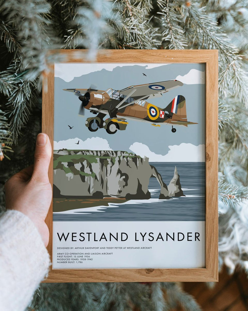 Hands holding a framed Westland Lysander print in front of a frosted fir tree